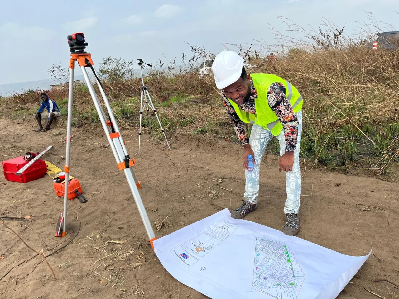 Un professionnel équipé d’un casque et d’un gilet effectue un relevé avec un appareil topographique